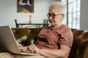 senior woman sitting on her home sofa engaging in online counseling for seniors
