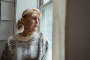 senior woman looking out the window with sadness